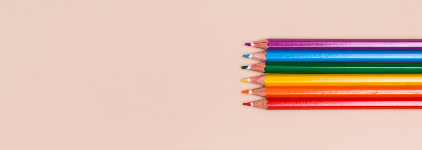 Hintergrund: Rosa Vordergrund: rechts, 6 Buntstifte übereinander welche die Pride Farben haben