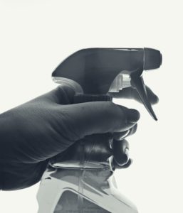 Hand hält eine Reinigersprühflasche